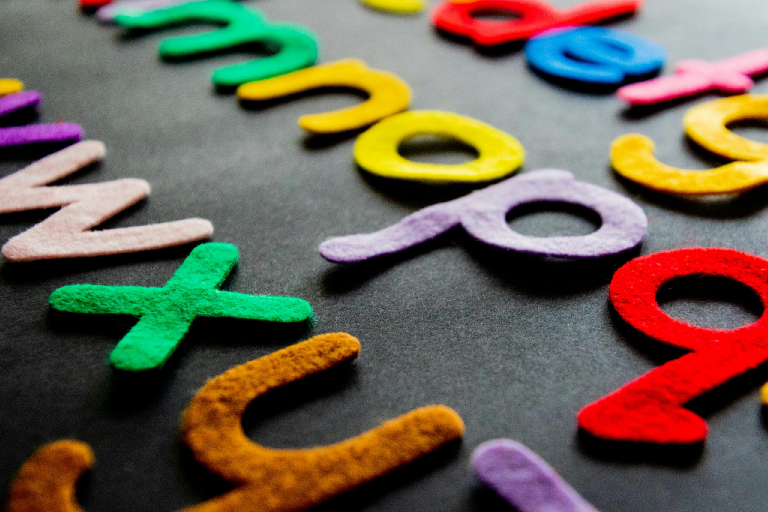 Colorful felt alphabet letters displayed on a dark background.